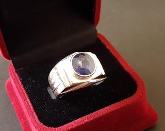 May include: A silver ring with a dark blue gemstone set in a bezel setting. The ring has a textured band.