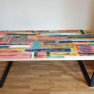 May include: A rectangular wooden table with a colorful geometric pattern on the top. The table has black metal legs.