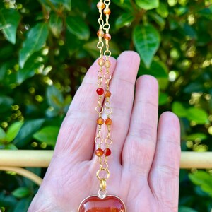 May include: A gold chain necklace with carnelian beads and a large carnelian heart pendant.