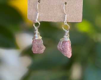 May include: A pair of silver wire wrapped earrings with pink gemstone accents.