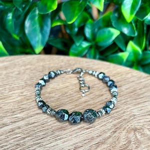 May include: A black beaded bracelet with a silver clasp. The beads are faceted and have a rough, textured surface.
