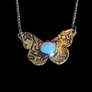 May include: A gold butterfly pendant necklace with a light blue opal gemstone in the center. The butterfly wings are textured and detailed.