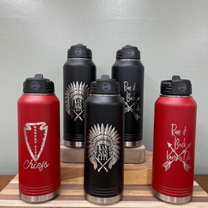 May include: Five stainless steel water bottles with different designs. The bottles are red and black with silver lids. The designs include a Native American headdress, an arrow, and the words "Run it Back Kansas City".