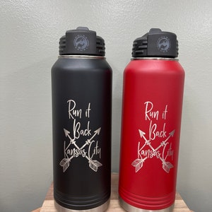 May include: Two stainless steel water bottles with black and red powder coated finishes. Both bottles have a silver lid with a logo that says "Polar Camel". The bottles have the text "Run it Back Kansas City" with crossed arrows engraved on the front.