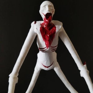 May include: A white, skeletal figurine with long limbs and a humanoid form. The figure has a gaping mouth and a red, blood-like substance covering its neck and chest. The figure is posed against a black background.