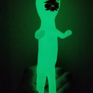 Puede incluir: Una figurita verde que brilla en la oscuridad de una persona con la cara negra y un sombrero puntiagudo.