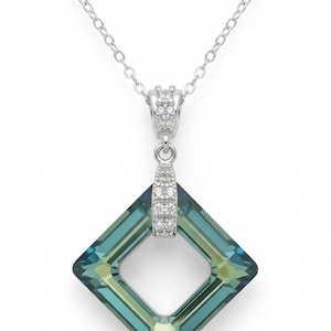 May include: A silver necklace featuring a square pendant with a teal and yellow-green crystal. The pendant has a diamond-shaped opening in the center and is accented with small, clear crystals. The chain is a delicate silver link.