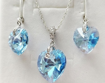 Colar em prata de lei 925 com cristal Swarovski em tom de água-marinha brilhante e brincos em prata de lei 925 com pingente de coração em cristal Swarovski em tom de água-marinha.