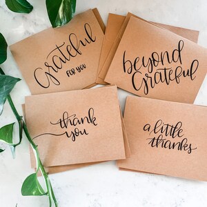 May include: Set of five kraft paper cards with handwritten calligraphy in black ink. The cards feature the phrases "Grateful for you", "Beyond Grateful", "Thank you", "A little thanks", and "Thank you".