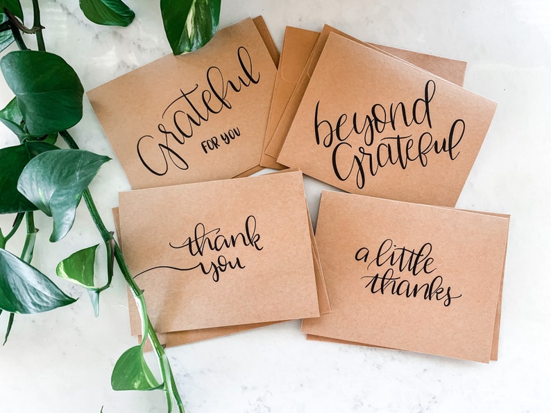 May include: Set of five kraft paper cards with handwritten calligraphy in black ink. The cards feature the phrases "Grateful for you", "Beyond Grateful", "Thank you", "A little thanks", and "Thank you".