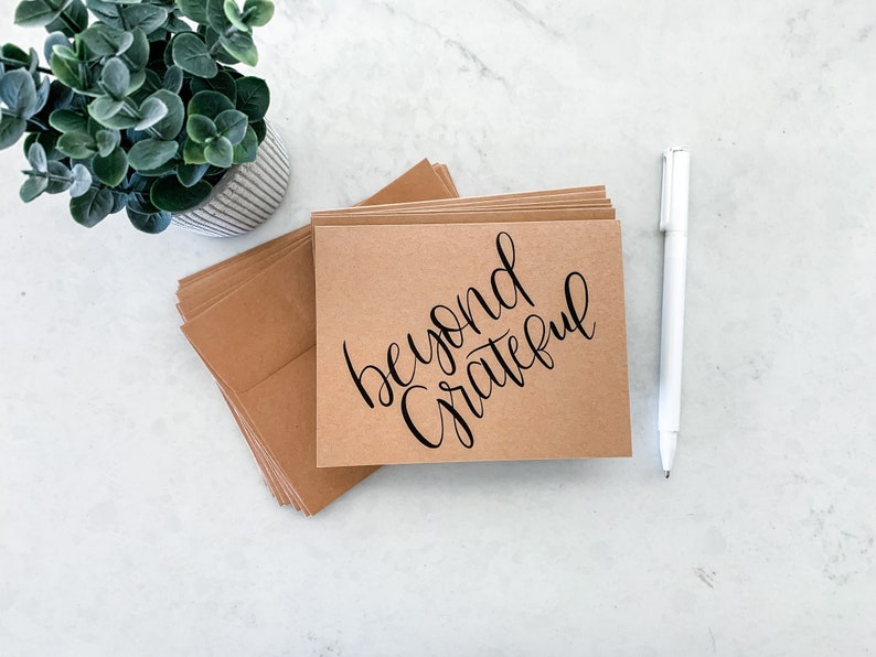 May include: A stack of brown kraft paper cards with the text "beyond grateful" written in black calligraphy.