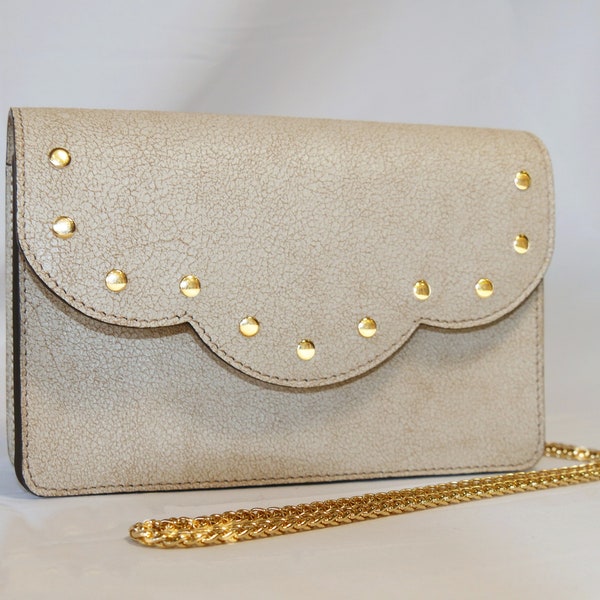 Pochette Agathe en cuir blanc cassé craquelé beige avec un rabat festonné à rivets dorés, fabriqué en France