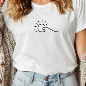 Puede incluir: Camiseta blanca con un dibujo minimalista en negro de un sol y una ola. El gráfico está centrado en el pecho. La camiseta está hecha de un material suave y ligero, adecuada para el uso diario.