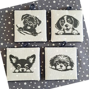 Peut inclure: Quatre dessous de verre carrés en tissu gris clair avec des portraits de chiens brodés en noir et blanc. Chaque dessous de verre présente un motif de race de chien différent, avec une boucle en corde bleue. Le tissu de fond a un motif d'étoiles blanches.