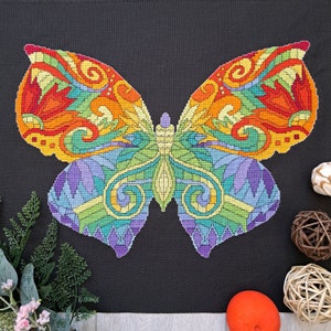 May include: A colorful butterfly with intricate patterns in shades of orange, yellow, green, blue, and purple. The butterfly is embroidered on a black fabric background.