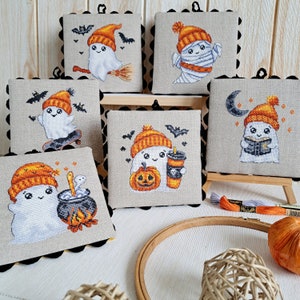 May include: Set of six embroidered pillow covers featuring cute ghost designs with Halloween themes. Each pillow cover has a different design, including a ghost holding a pumpkin, a ghost with a coffee cup, a ghost reading a book, and a ghost with a cauldron. The pillow covers are made of a soft, white fabric with a beige background.