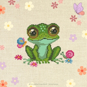 May include: Cross-stitch design featuring a friendly green frog with large eyes, a butterfly, and a snail. The frog is surrounded by flowers and butterflies on a beige background. The text "Artmishka Cross Stitch - Anna Gutova" is at the bottom.