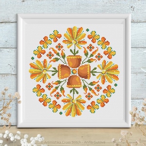 May include: A cross stitch pattern featuring a circular design of orange and yellow flowers in pots. The flowers are surrounded by smaller orange and yellow flowers.