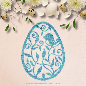 Può includere: Un motivo a punto croce blu e verde di un uovo di Pasqua con un uccello e un motivo floreale. Il testo "Artmiskha Cross Stitch - Anna Gutova" è in basso nell'immagine.