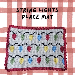 May include: Crocheted place mat featuring a string of colorful Christmas lights. The mat has a white background with red, green, yellow, and blue lights. The border is red with a scalloped edge. Text on the mat reads "STRING LIGHTS PLACE MAT".