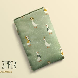 May include: A rectangular, sage green pouch with a repeating pattern of white geese wearing hats and scarves. The text "NO ZIPPER" and "senza cerniera" are printed in black at the bottom. The pouch is a soft, fabric material.