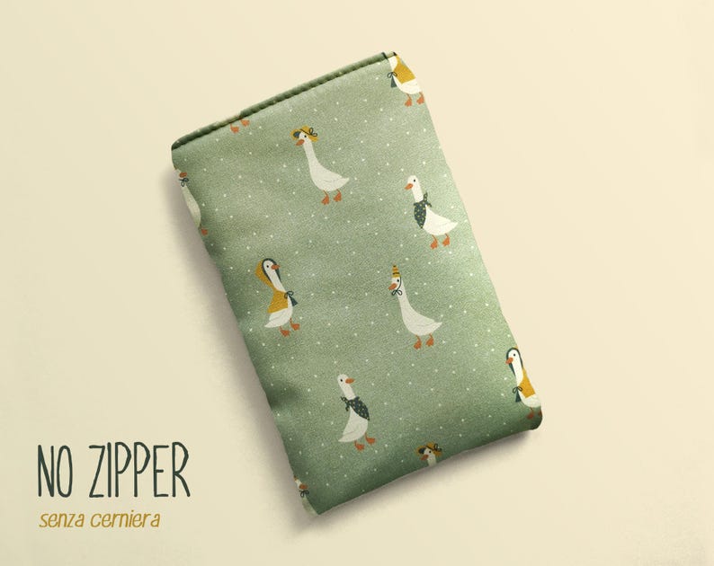 May include: A rectangular, sage green pouch with a repeating pattern of white geese wearing hats and scarves. The text "NO ZIPPER" and "senza cerniera" are printed in black at the bottom. The pouch is a soft, fabric material.