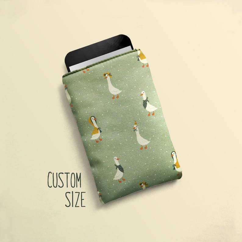 May include: A green phone sleeve with a pattern of geese wearing hats and scarves. The text "CUSTOM SIZE" is printed on the lower left. A black phone is partially visible inside the sleeve.