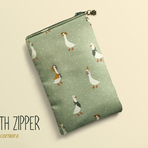 May include: A rectangular, sage green zippered pouch with a whimsical pattern of white geese wearing hats and bow ties. The text "WITH ZIPPER" and "con cerniera" are printed on the lower left.