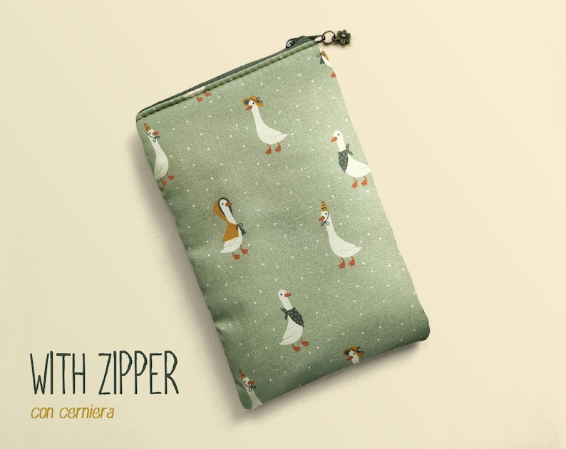May include: A rectangular, sage green zippered pouch with a whimsical pattern of white geese wearing hats and bow ties. The text "WITH ZIPPER" and "con cerniera" are printed on the lower left.