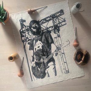 May include: Black and white print of a person playing a guitar. The person is wearing a shirt with the letters "HA" on it. The print is on a white background with the text "DIY & ARTWORK GALLERY" at the bottom.