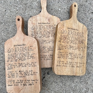 K&ouml;nnte beinhalten: Drei Holzschneidebretter mit handgeschriebenen Anweisungen zum Kochen von chinesischem Reis. Die Anweisungen sind in Kursivschrift geschrieben und beinhalten Details zu Garzeiten, Zutaten und der Zubereitung des Reises.