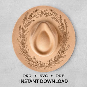 May include: A tan fedora-style hat with a decorative floral wreath design. The hat has a wide brim and a rounded crown. The floral design is a dark brown color. The text "PNG • SVG • PDF INSTANT DOWNLOAD" is at the bottom.