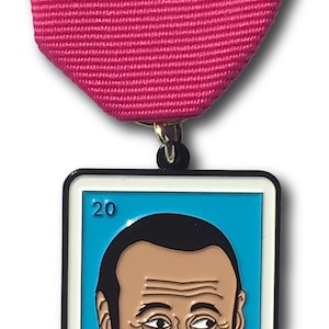 May include: A metal pin in the shape of a Loteria card. The card is blue with a white border and features a cartoon illustration of a man with a beard and a big smile. The number 20 is in the top left corner and the text "EL CONTUSION" is at the bottom.