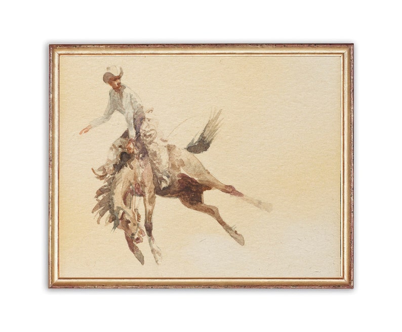 Puede incluir: Una pintura de acuarela de un vaquero montando un caballo que se encabrita. El vaquero lleva un sombrero blanco y una camisa de color claro. El caballo es marr&oacute;n y blanco y est&aacute; en el aire. La pintura est&aacute; enmarcada en un marco dorado.