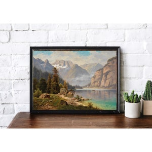May include: A framed landscape painting depicting a lake surrounded by mountains and trees. The lake is a vibrant blue, and the mountains are a soft gray. The trees are a deep green, and the sky is a light blue.