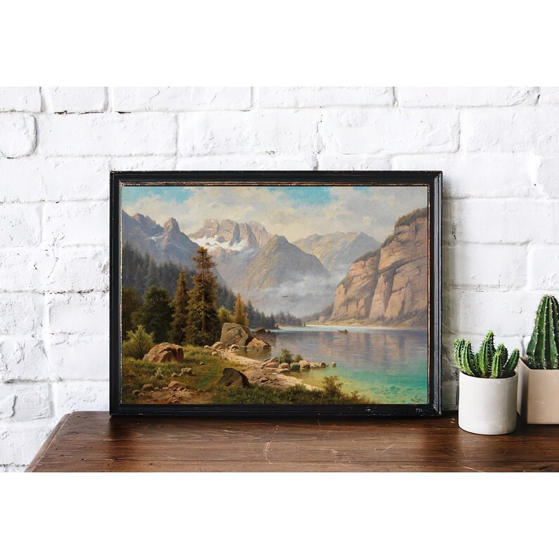 May include: A framed landscape painting depicting a lake surrounded by mountains and trees. The lake is a vibrant blue, and the mountains are a soft gray. The trees are a deep green, and the sky is a light blue.