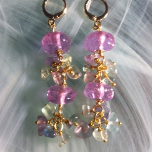 May include: A pair of dangle earrings with pink and green glass beads. The earrings have gold-toned hoops and are connected with gold-toned chains.
