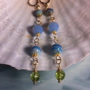 May include: Gold dangle earrings with blue and green glass beads. The earrings have a delicate chain and a variety of bead shapes.