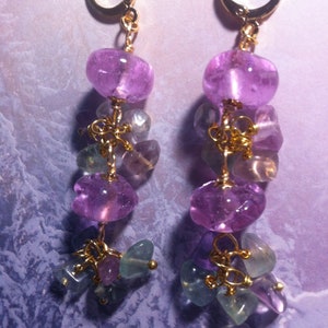 May include: A pair of dangle earrings with gold hoops and multiple purple and green gemstone beads.