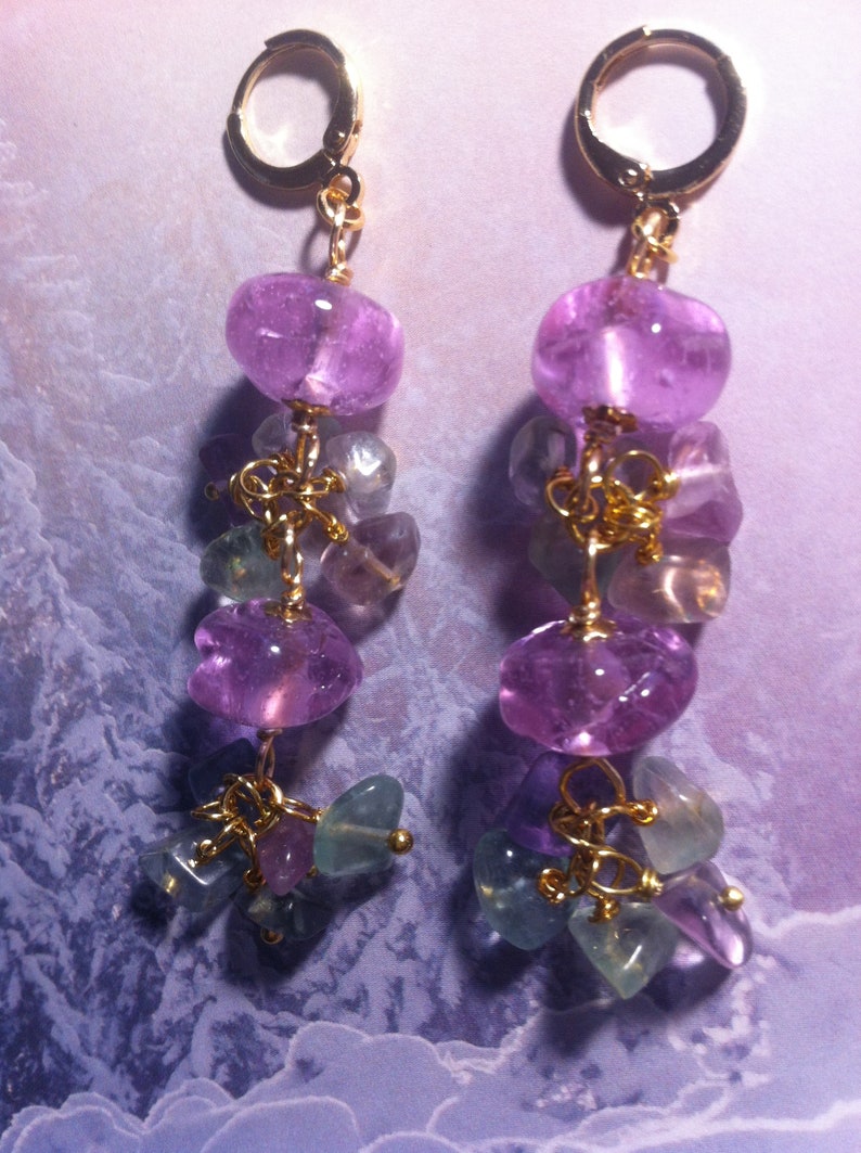 May include: A pair of dangle earrings with gold hoops and multiple purple and green gemstone beads.