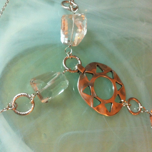 Pendant composed of large faceted rock crystal pebbles, a silver sun, a stainless steel charm and twisted rings