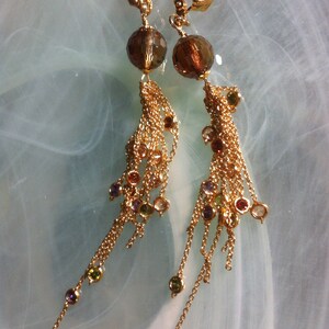 May include: A pair of gold dangle earrings with brown faceted beads and multi-coloured crystal accents.