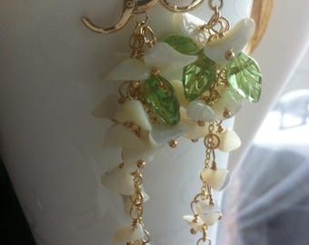 Earrings resembling branches of a large white magnolia tree, adorned with pearl nuggets of mother-of-pearl, and are set on a delicate chain