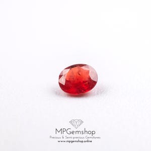 Peut inclure: Une pierre précieuse rouge, de forme ovale et facettée, posée sur un fond blanc. L'image contient également le texte "MPGemshop Precious & Semi-precious Gemstones www.mpgems.shop.online".