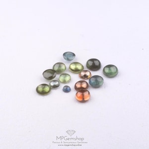 May include: A selection of polished gemstones in shades of green, blue, and copper. The gemstones are round and smooth, with a glossy finish. The image includes the text "MPGemshop Precious & Semi-precious Gemstones www.mpgemshop.online".