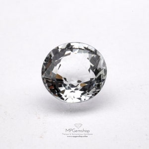May include: A clear, round, faceted gemstone against a white background.