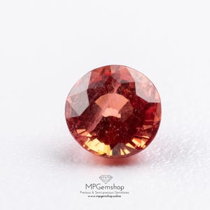 Peut inclure: Une pierre précieuse ronde et facettée, aux teintes rouges et orangées, sur fond blanc. L'image contient le texte "MPGemshop Precious & Semi-precious Gemstones www.mpgems.shop.online".