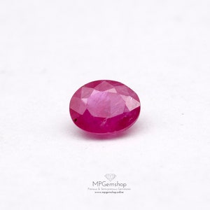 May include: A vibrant pink oval-shaped ruby gemstone with a faceted cut.