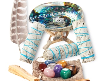 May include: A white sage smudging kit with a abalone shell, wooden stand, sage sticks, palo santo sticks, a feather, and a pouch of crystals. The kit is on a white background.