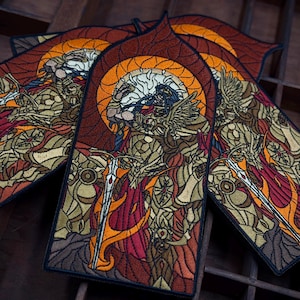 Peut inclure: Trois écussons brodés en forme d'arche représentant une illustration de style vitrail d'un guerrier en armure dorée tenant une longue épée. Le motif utilise une palette vibrante de fils orange, rouges, dorés et noirs avec des détails précis.